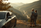 An older couple on a senior road trip pausing by their car at a scenic mountain overlook in warm morning light.